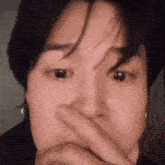 a close up of a person covering their mouth with their hands .