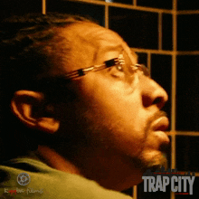 a man wearing glasses and a green shirt with the word trap city on the bottom