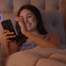 a woman is laying in bed looking at her phone and crying