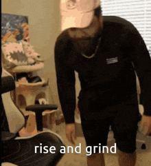 a man in a black shirt and shorts is standing in a room with the words rise and grind below him