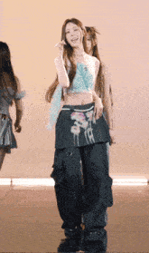 a woman in a crop top and cargo pants is dancing