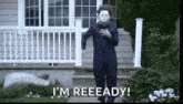 a man in a halloween costume is standing in front of a house with his hand on his chest .
