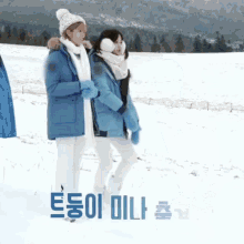 two women walking in the snow with korean writing on the bottom right
