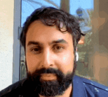 a man with a beard is wearing headphones and looking at the camera