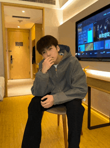 a man sitting on a chair in front of a tv with chinese characters on it