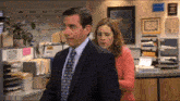 a man in a suit and tie is standing next to a woman in front of a reception desk
