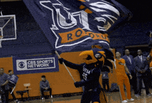 a cbs sports network ad is behind a mascot holding a flag