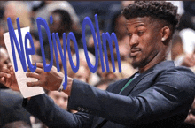 a man in a suit is holding a piece of paper with the words ne divo olm written on it