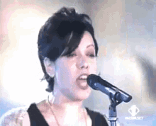 a close up of a woman singing into a microphone with the word media set in the corner