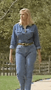 a woman in a denim jumpsuit and jeans is walking down a sidewalk
