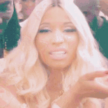 a woman with blonde hair is standing in front of a group of men and making a funny face .