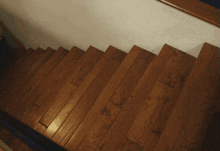 a person walking down a set of wooden stairs with a white wall behind them