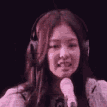 a woman wearing headphones is holding a microphone and singing into it .