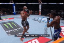two men are fighting in a boxing ring with monster energy advertisements on the floor
