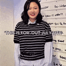 a woman wearing a black and white striped shirt is smiling in front of a wall that says this is for out july 11th