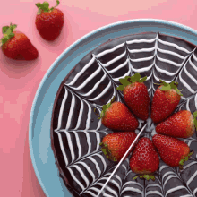 a chocolate cake with strawberries on top and a spider web design