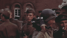 a group of soldiers are standing in front of a building with one wearing a helmet and goggles