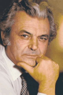 a man with gray hair is wearing a white shirt and striped tie