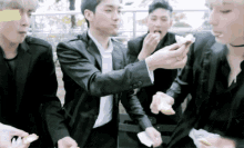 a group of young men in suits are eating food