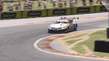 a race car is going around a curve on a track with a sign that says ' simpson ' on it