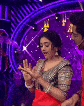 a woman in a red saree is dancing on a stage