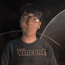a man wearing glasses and a black shirt with the word vincent on it