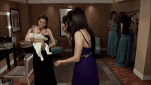 a woman in a purple dress holding a baby