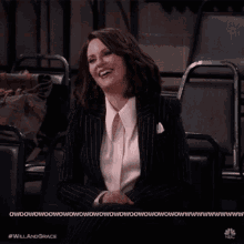 a woman in a suit is sitting in a chair and smiling with the words will and grace below her
