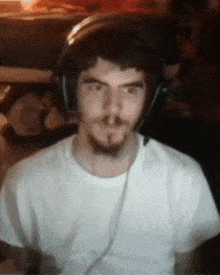 a man wearing headphones and a white t-shirt looks at the camera