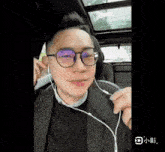 a man wearing glasses and ear buds is sitting in a car .