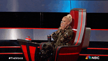 a woman is sitting in a chair with a nbc logo on it