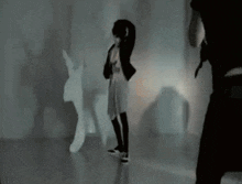 a woman is standing in front of a wall with a rabbit shadow on it .