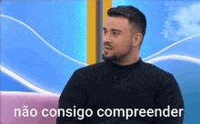a man in a black sweater is sitting on a pink couch with the words não consigo compreender behind him