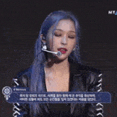 a woman with blue hair is wearing a microphone and waving her hand