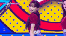 a woman in a red shirt is dancing on a colorful stage