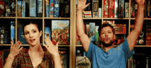 a man and a woman are standing in front of a shelf of board games including one called watergate