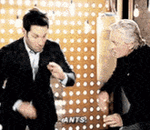 two men are dancing in front of a wall that says ants on it .