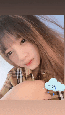 a girl in a plaid shirt is holding a cloud with a sad face