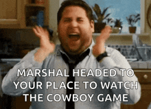 a man in a kitchen with a caption that says marshal headed to your place to watch the cowboy game ..