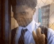 a man in a suit and tie is standing behind a glass door .