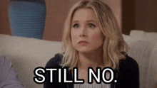 a woman is sitting on a couch with a sign that says still no .