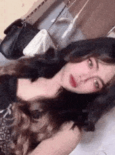 a woman with long hair is laying on a bed with a purse .