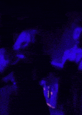 a man in a striped shirt is standing in a dark room with purple lights