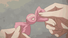 a person is holding a piece of pink paper with a red heart in the middle