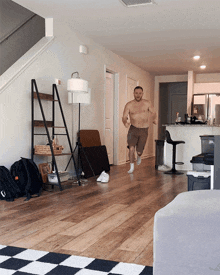 a shirtless man running in a living room
