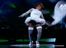 a woman in a white dress is dancing on a stage in front of a sign that says amahioverdose