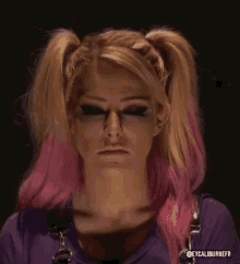 a woman with pigtails and pink hair is making a funny face while wearing a purple shirt .