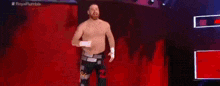 a shirtless wrestler is walking out of a ring .
