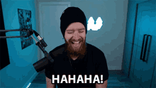 a man with a beard is laughing while standing in front of a microphone and the word hahaha is on the bottom