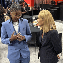 a woman in a blue suit talks to a woman in a black suit